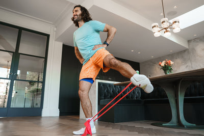 Man exercising with resistance bands in a modern living room.