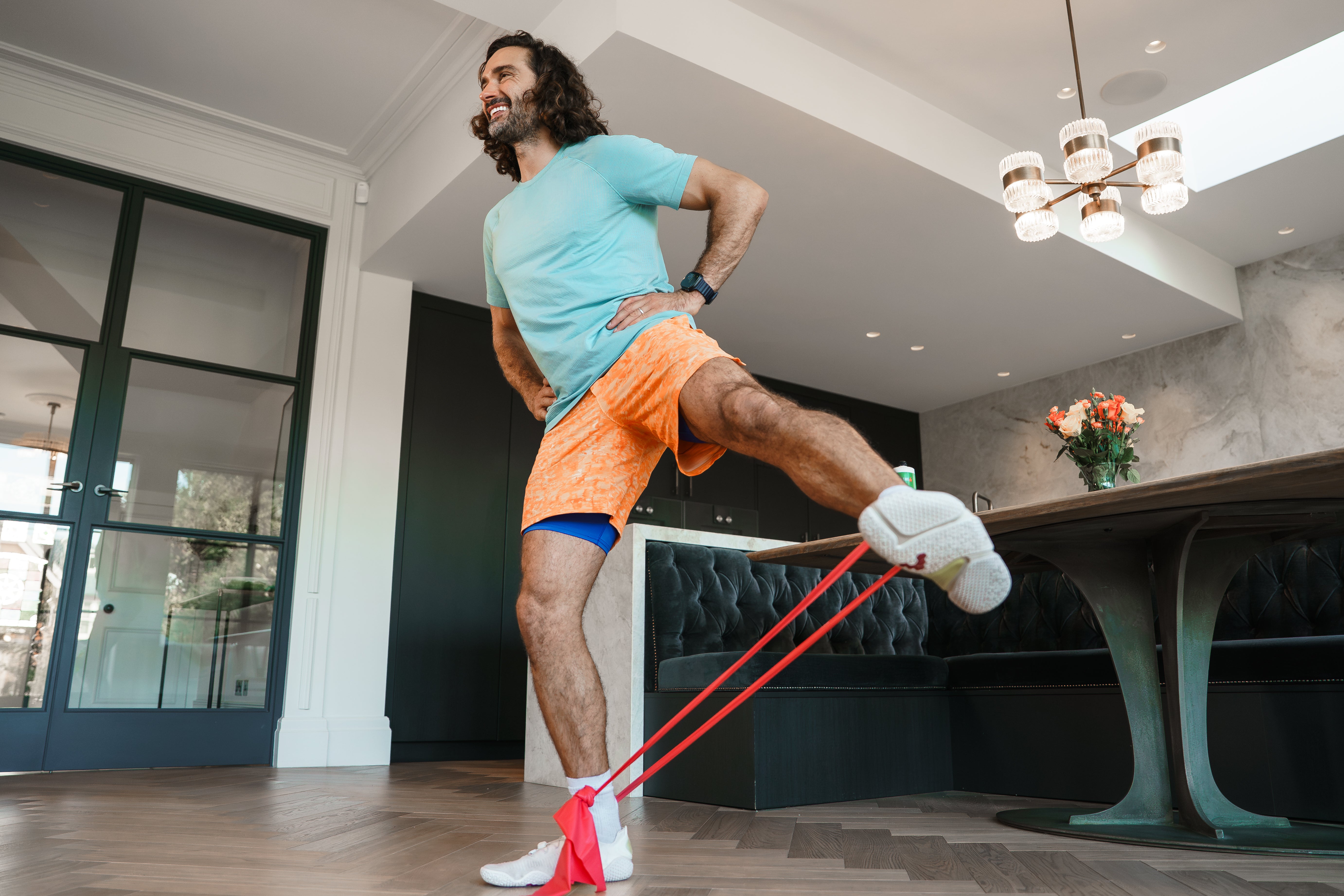 Man exercising with resistance bands in a modern living room.