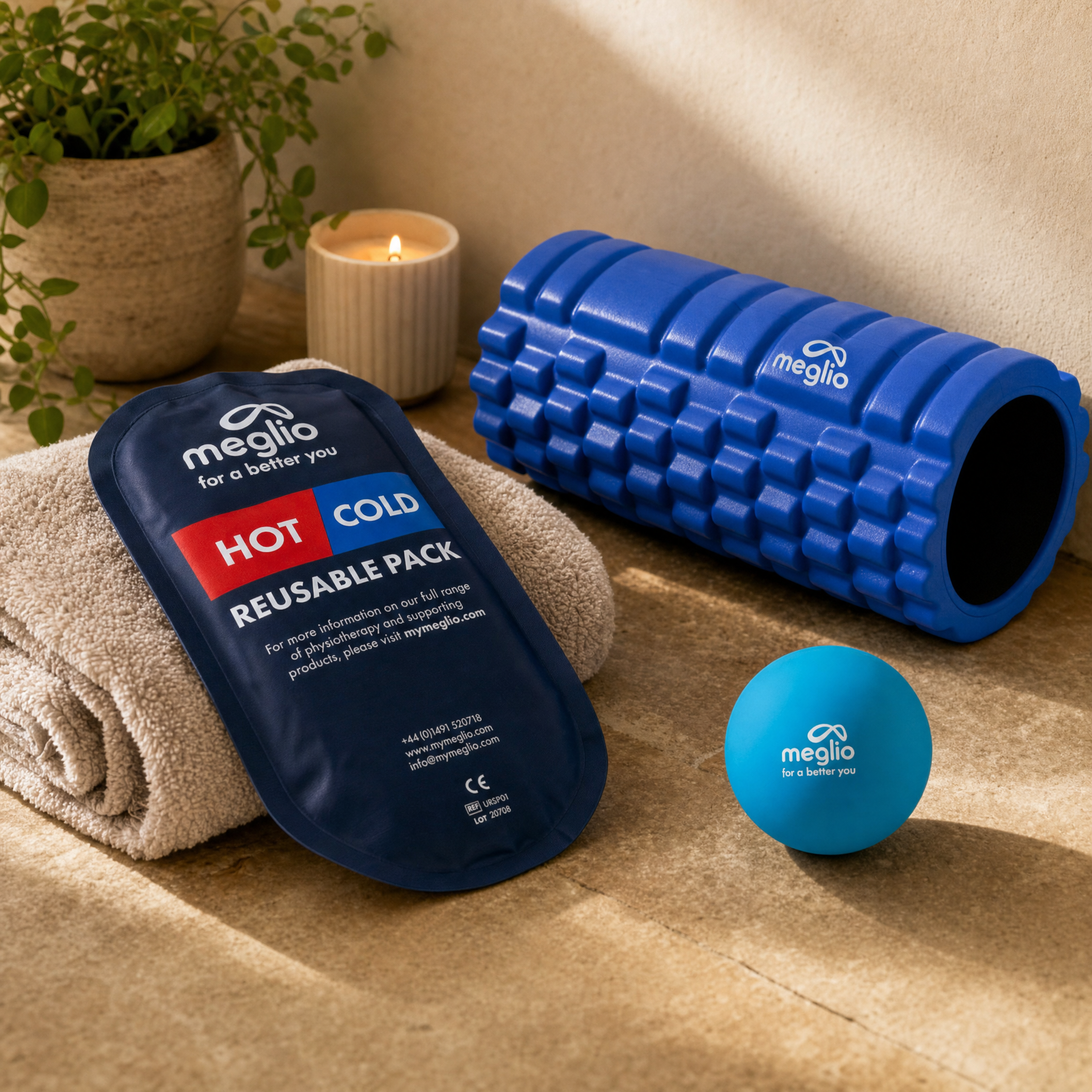 flexa.fit grid foam roller, hot and cold pack and massage ball beside a rolled towel