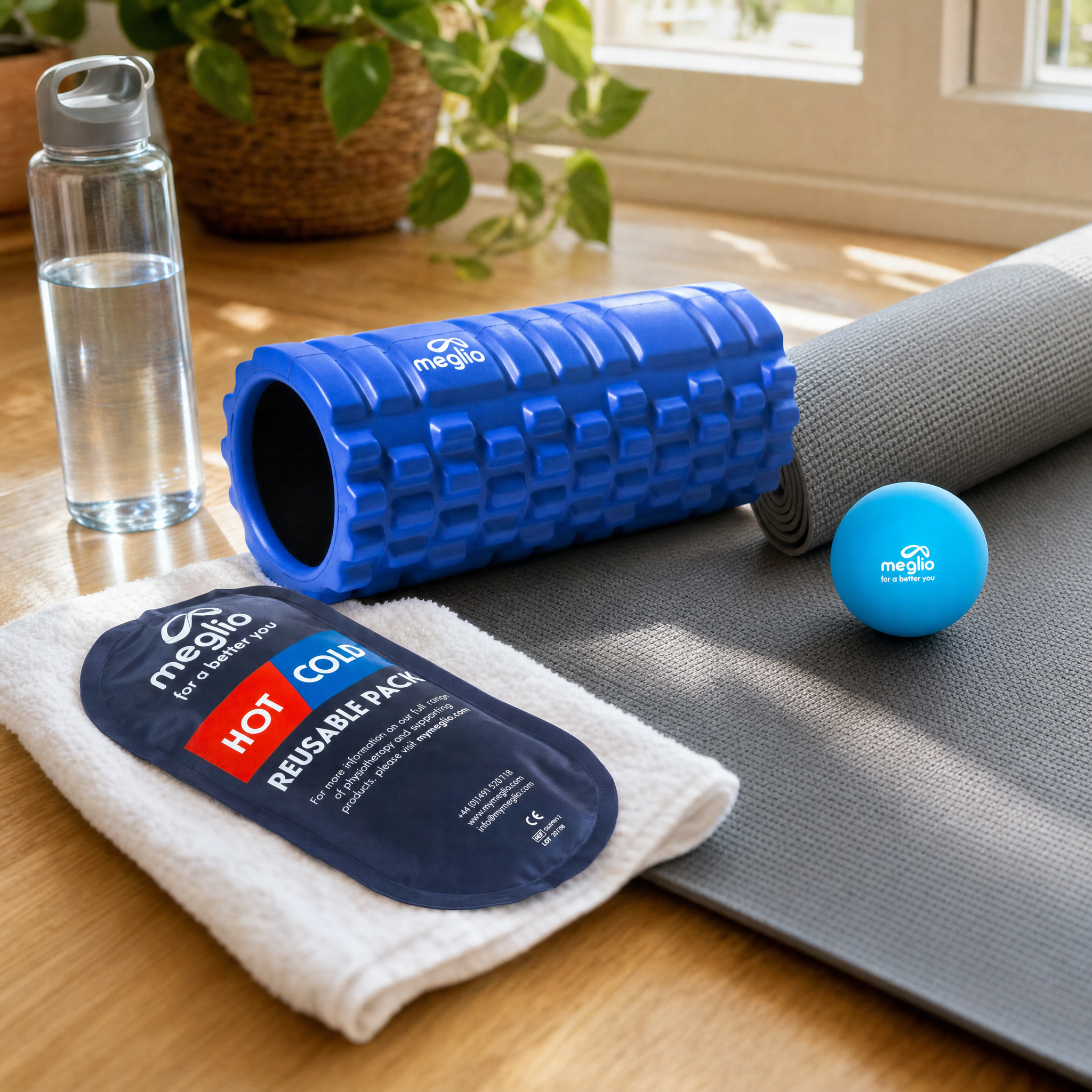 flexa.fit recovery kit laid out at home with the grid foam roller, hot and cold pack, massage ball and a water bottle